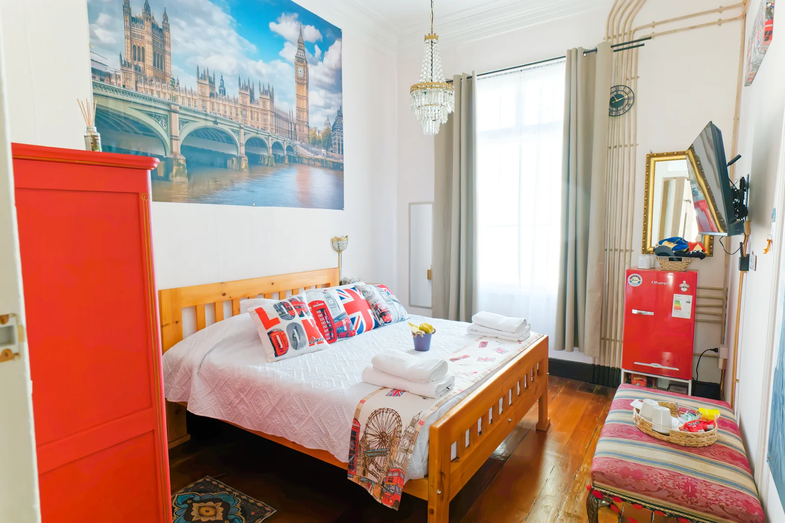 Cama, armario rojo y ventana en la habitación Inglaterra de CasaFran